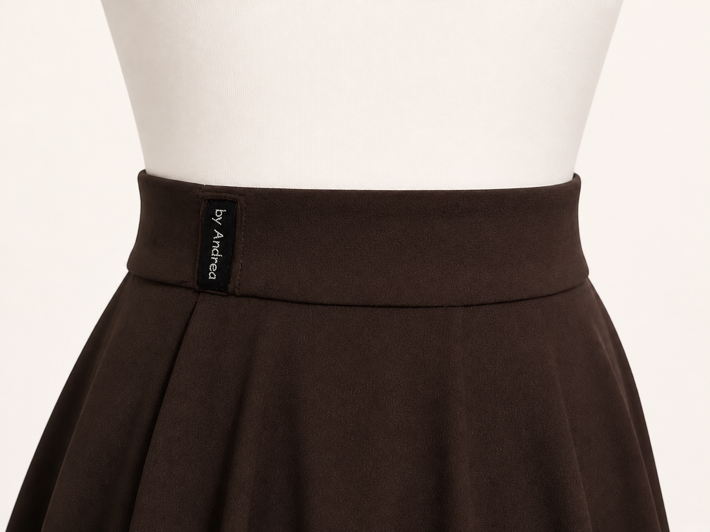 Detalle de la cinturilla con ojal de una saya marrón oscuro sobre un maniquí blanco